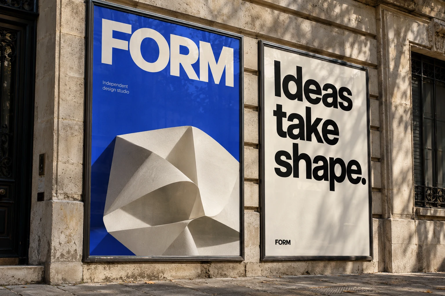 Cobalt and ivory FORM campaign posters in metal frames on a sunlit limestone facade, with the headline Ideas take shape